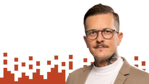 Portrait Mathieu Coquelin Ein Mann mit Brille blickt in die Kamera und lächelt. Hinter ihm eine Grafik mit roten Quadraten.