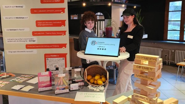 Lena und Nesrin am Stand von der Fachstelle Extremismusdistanzierung Zwei junge Frauen stehen an einem Info-Stand der Fachstelle Extremismusdistanzierung mit verschiedenen Info-Materialien